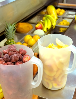 Strawberry, Pineapples, Peaches, and fresh fruits on stainless steel juice bar